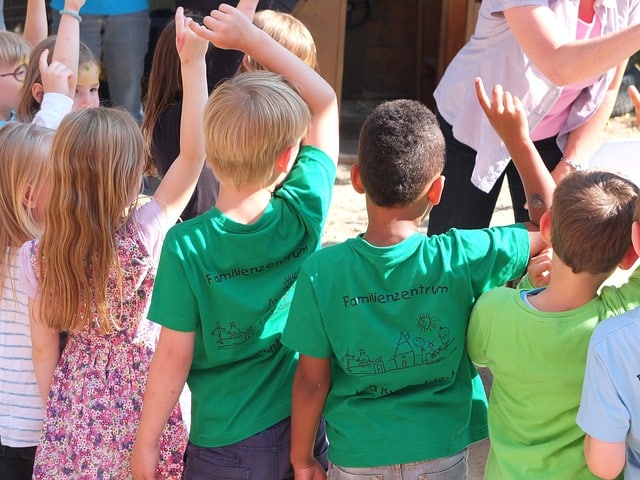 Childrens rising their hands to answer questions in class