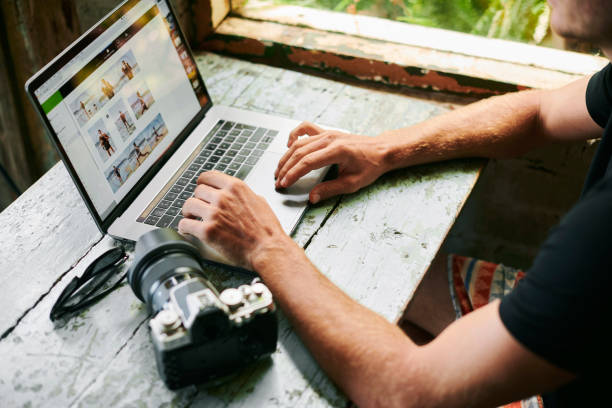 Male photographer on laptop trying to sell photos
