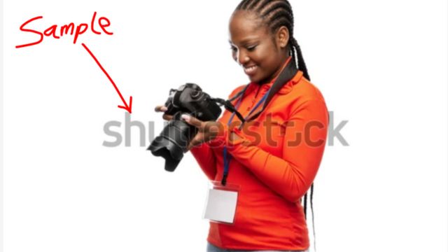 A black lady  looking at a camera in her hand.