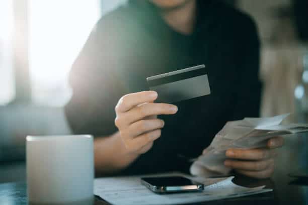 image of a young man hold a debit card with cash on the other hand.